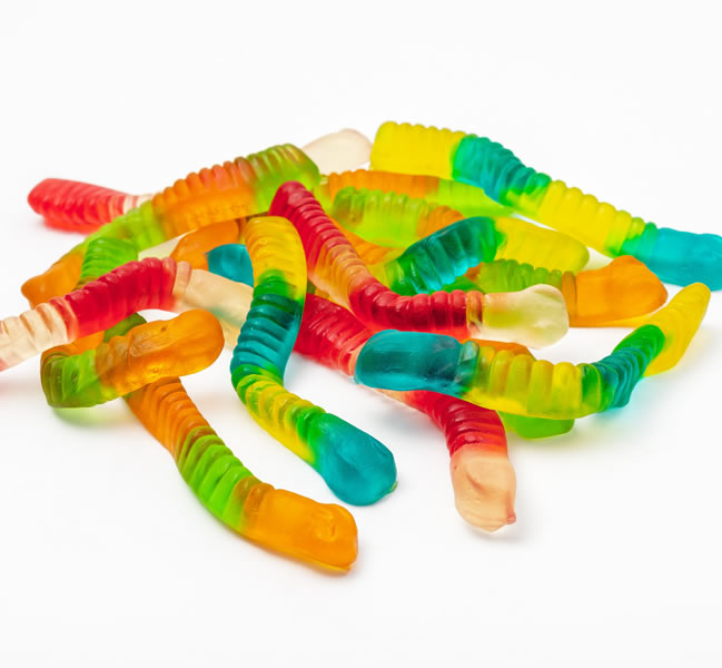 Rainbow colored gummi worms on white background