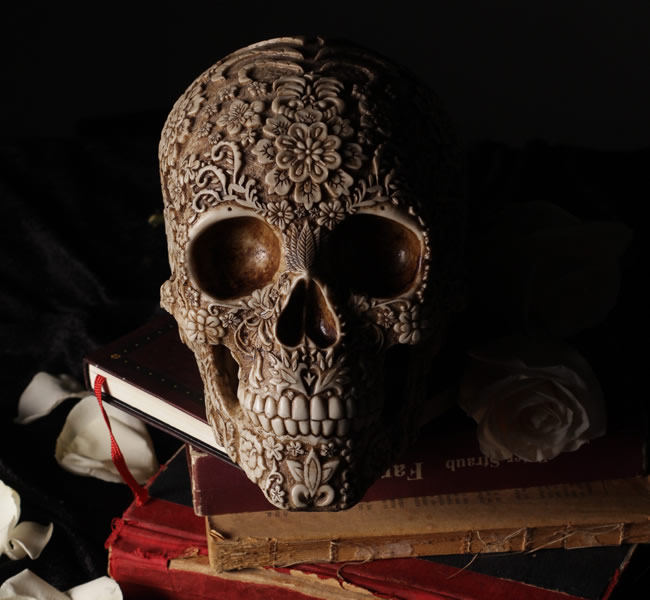 Skull with carved designs posed on top of old book