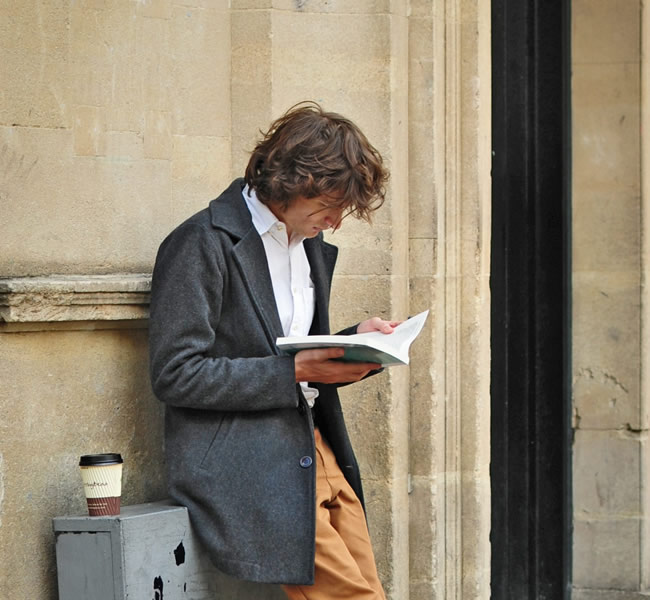Man standing outdoors reading